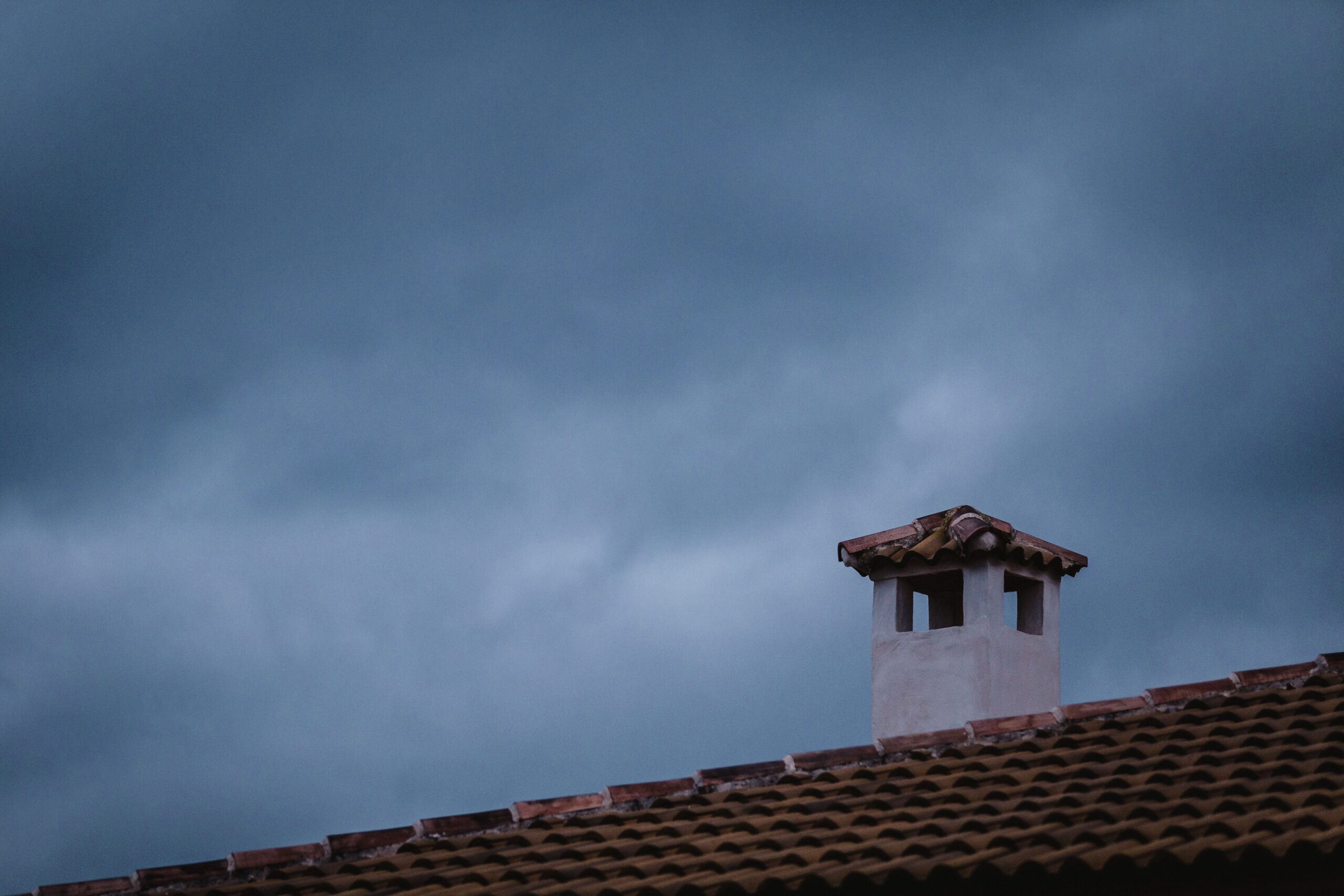 Przewód kominowy na dachu na tle niebieskiego nieba